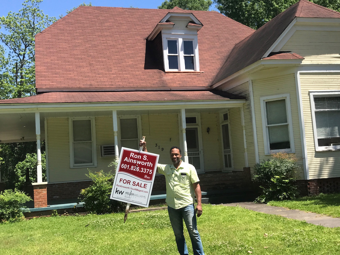 Man holding sold sign in front of house